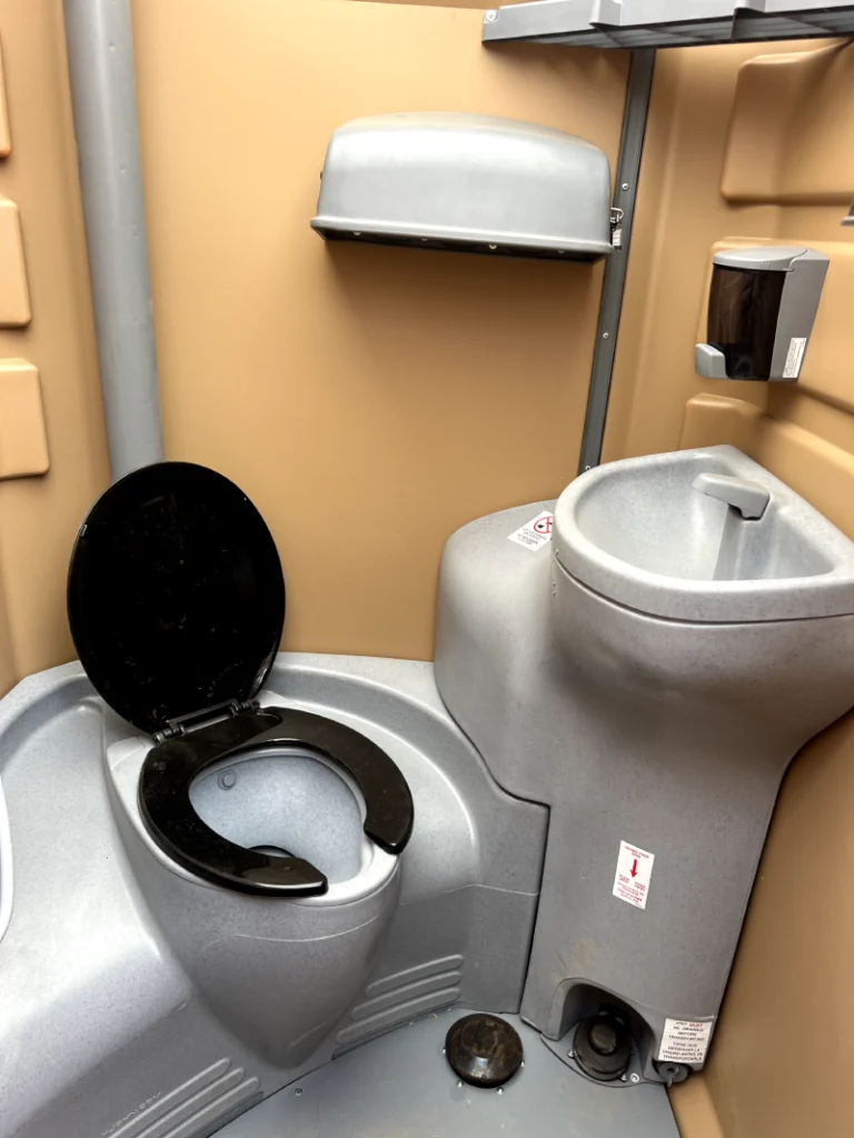 interior of a well-maintained portable toilet rental showing clean seat and hand sanitizer dispenser