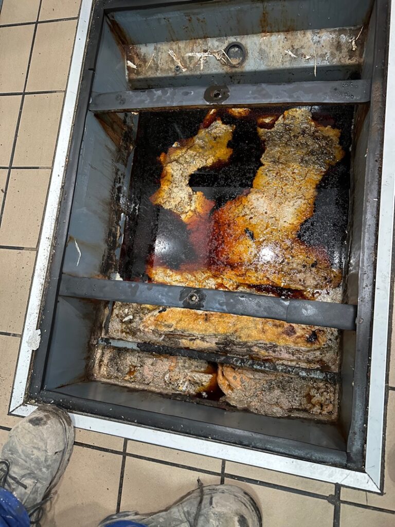 Severely clogged grease trap with hardened grease buildup at a commercial restaurant in Kamloops, BC