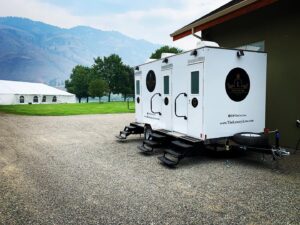 The Lux Loo portable washroom trailer set up on a gravel surface at an outdoor venue in BC.
