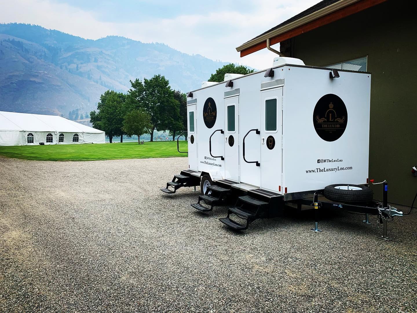 The Lux Loo portable washroom trailer set up on a gravel surface at an outdoor venue in BC.