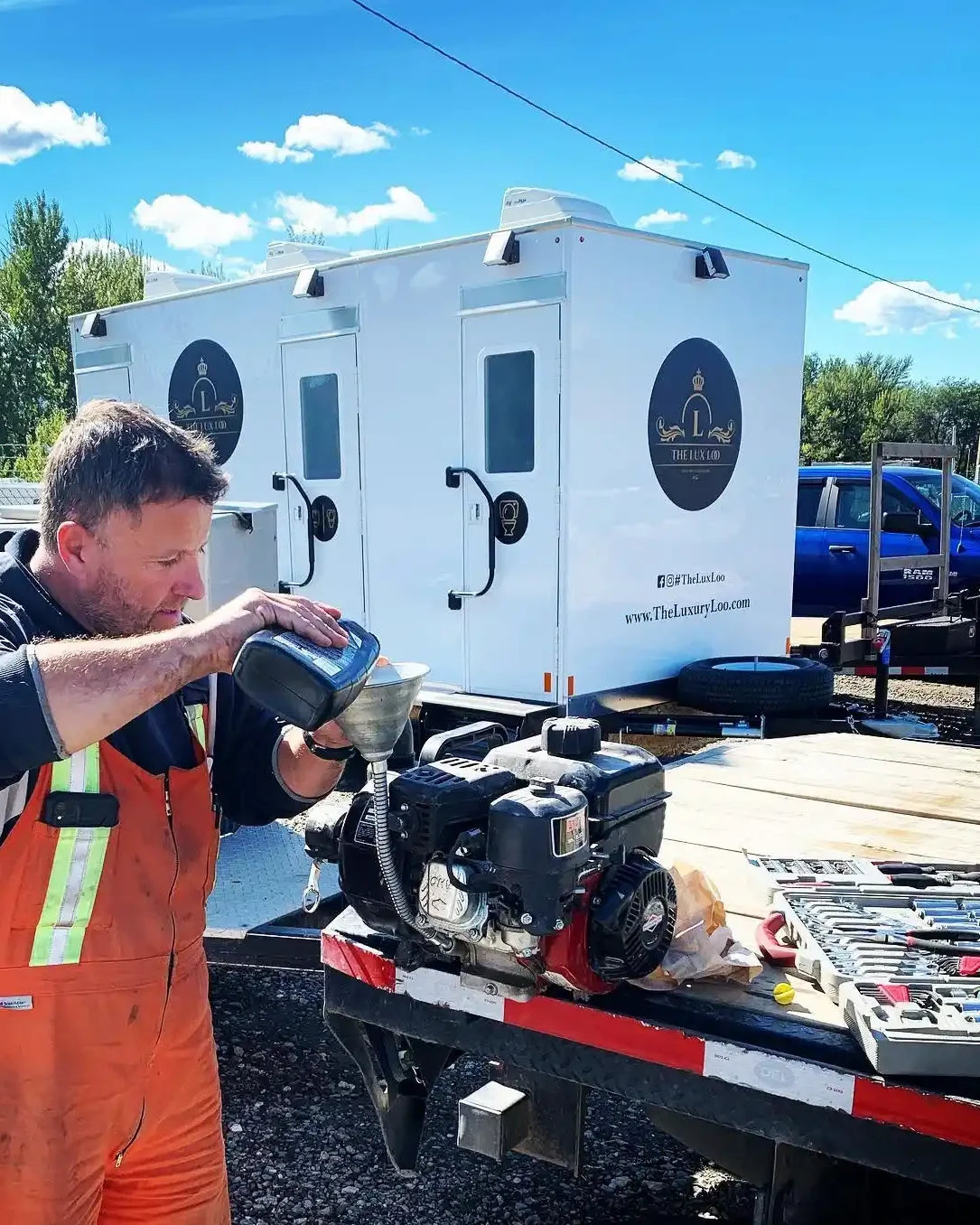 Worker servicing a portable generator beside The Lux Loo washroom trailer in BC